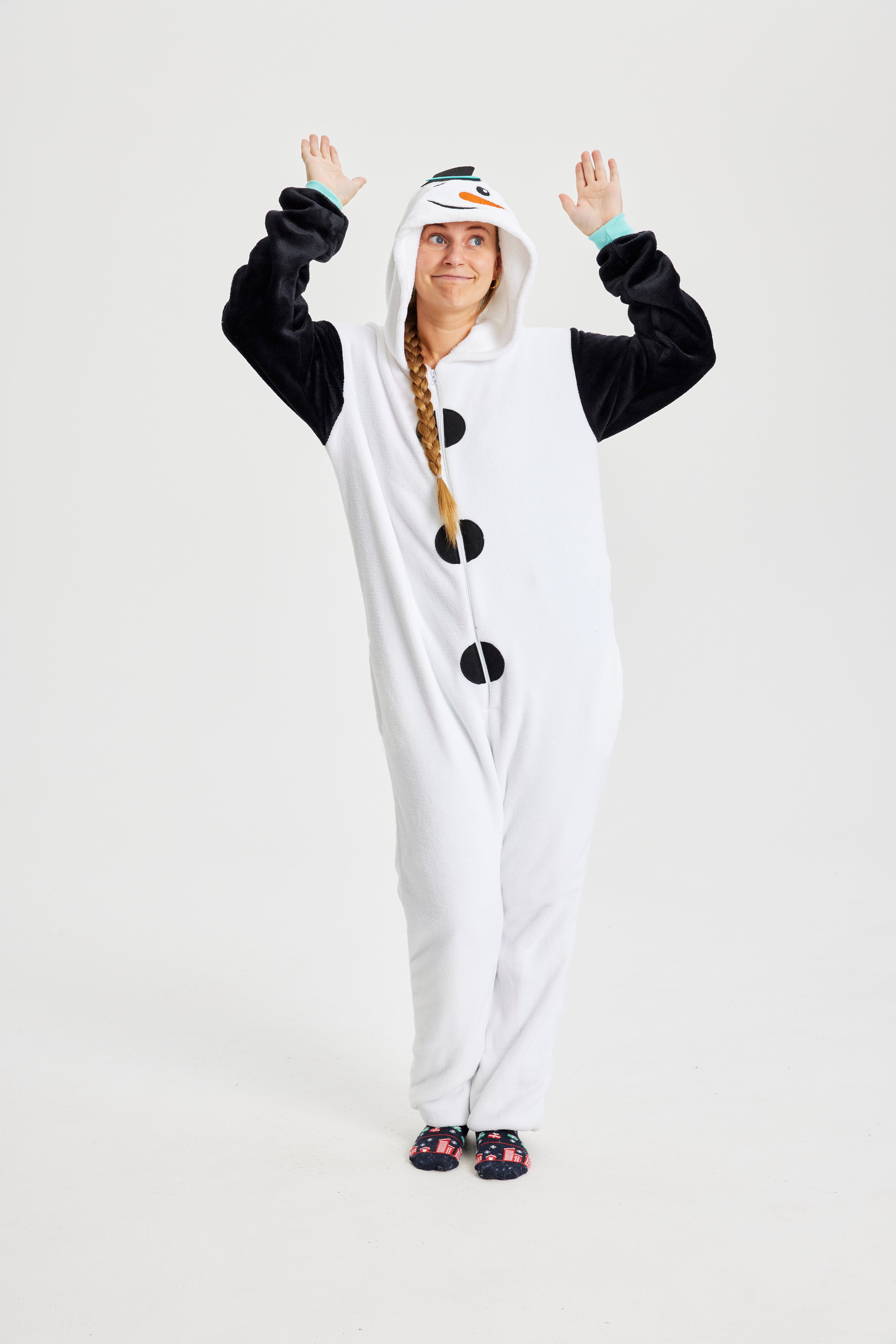 En kvinde med hænderne i vejret iført en jumpsuit, der ligner en snemand.